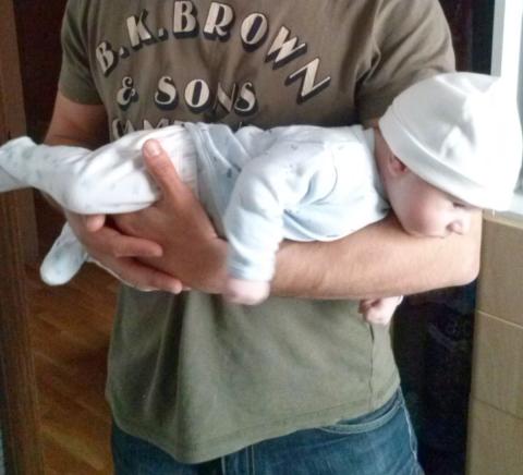 A father holding his baby with her/his face facing the ground