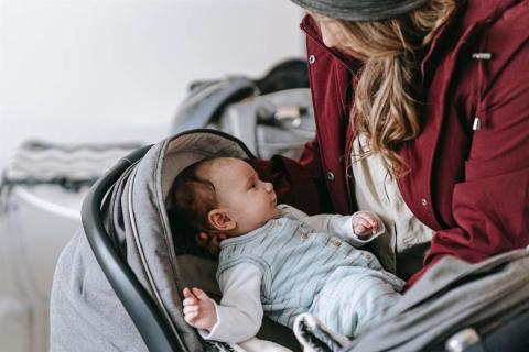 A mother putting her baby to a stroller