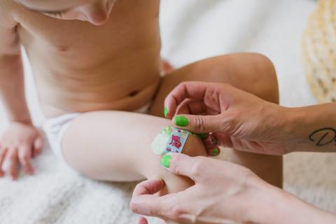 Adult putting a band aid onto a toddler's knee