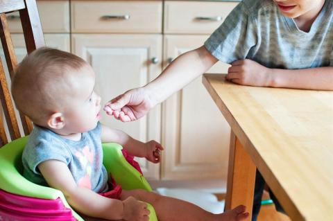 sibling giving baby a sweet