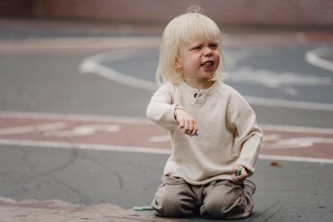 A child holding a peace of chalk and demanding something 