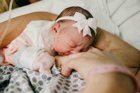 Mother breastfeeding newborn daughter in the hospital