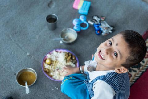 Boy sitting on the ground eating 