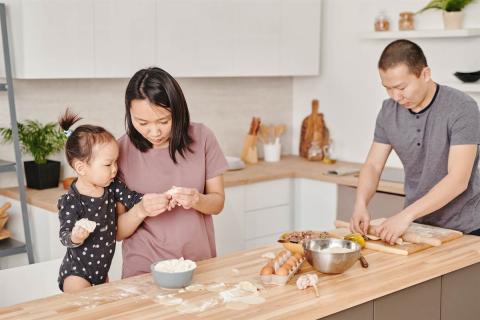 Father and mother preparing food with their toddler