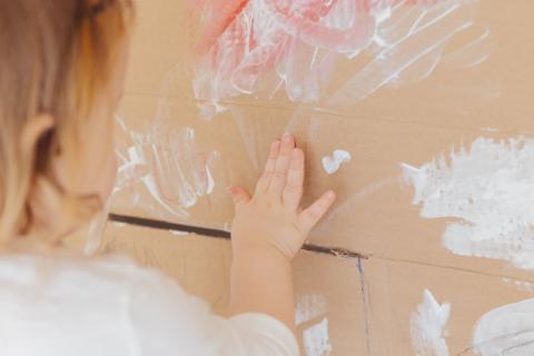 Toddler finger painting on cardboard