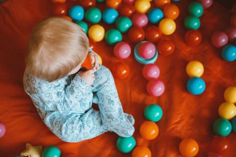 toddler sitting surrounded by many balls