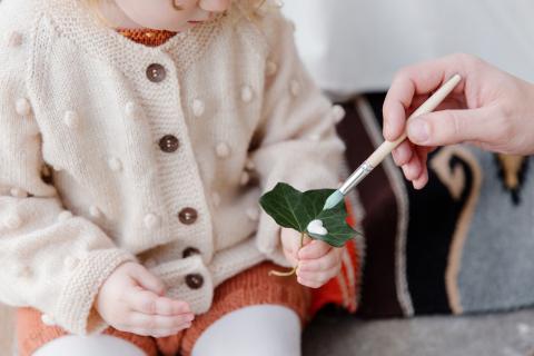 girl holding leaf covered in paint 