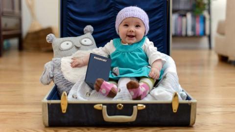 маленька дитина з паспортом сидить у валізі