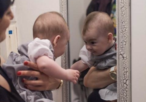 Caregiver holds infant in front of mirror
