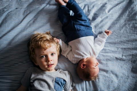 Young child sitting next to baby sibling