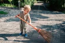 A toddler sweeping the ground