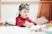 A toddler scribbling with crayon