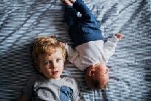 Young child sitting next to baby sibling