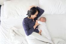 Woman lying in bed next to her newborn